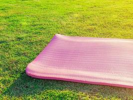 colchoneta de yoga rosa colocada sobre hierba verde en el parque por la noche había una suave luz del sol. los tonos cálidos y claros son adecuados para ejercicios de yoga. foto