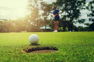 golf player putting golf ball into hole photo