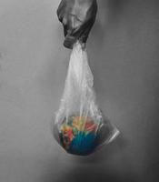 hand holding globe in plastic bag on black background concept earth day photo