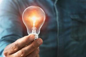 businessman hand holding lightbulb with sunshine. concept saving energy power photo