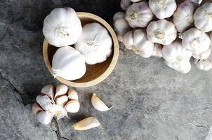 vegetales de ajo en un tazón de madera sobre fondos de mesa de madera antiguos foto