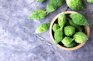 Fresh Bitter gourd vegetable in wooden bowl on old wood table backgrounds above photo