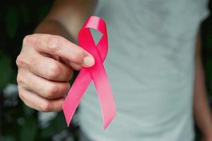 concepto de salud y medicina. mano que sostiene la cinta rosa. conciencia del cáncer de mama. señal de esperanza foto