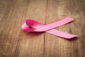 cinta rosa sobre madera. conciencia del cáncer de mama. concepto de salud y medicina foto