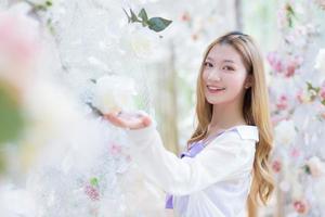 Asian beautiful lady smiles and stands in white rose flower garden as natural , luxury theme photo