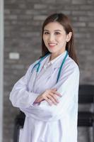 Asian female doctor with black long hair wears a white lab coat and stethoscope. photo