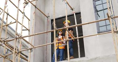 4K low angle view . A young male and female Asian civil engineers holding a tablet and working together at balcony . video