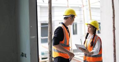 A young male and female Asian civil engineers holding a tablet and working together video