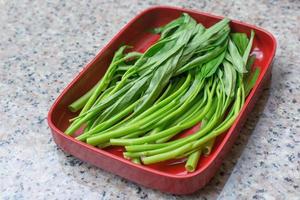 La gloria de la mañana china verde fresca picada como verdura tailandesa se sirvió en el restaurante shabu o sukiyaki en un plato rojo. foto