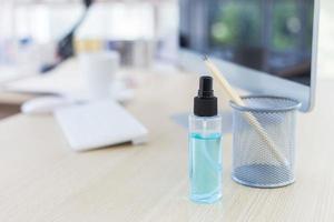 Disinfectant alcohol spray on the office desk in the home office with a blurred background. photo