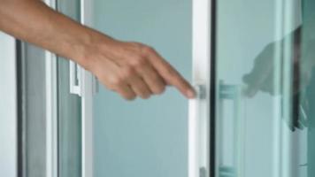 close-up van iemands hand die een glazen deur sluit. video