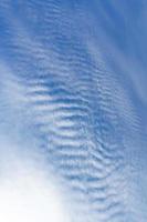 White clouds like a sea wave shape in the light blue sky as background. photo