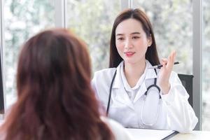 Asian professional female doctor give suggestion of healthcare information to her patient in examination room at hospital. photo