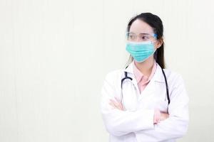 Asian woman doctor in white lab coat wears medical face mask and face shield photo