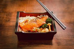 salmón teriyaki con arroz y vegetales con palillos. foto