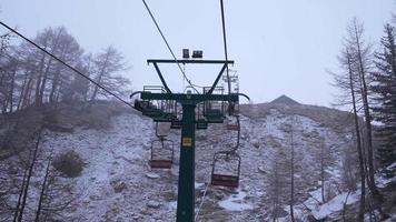 Leerer Sessellift in einem Skigebiet an einem nebligen, bewölkten Tag. wintersaison in den alpinen bergen. video