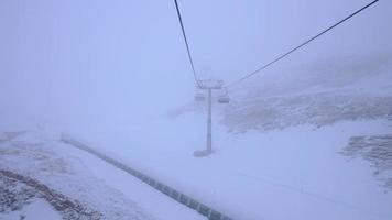 seggiovia vuota in una stazione sciistica in una giornata nuvolosa nebbiosa. stagione invernale nelle montagne alpine. video