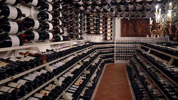 Weinflaschen mit Schnapsgläsern in einem Bunker im modernen Weinladen. Konzept der traditionellen Weinbereitung im Weingut. große Lagerung von Weinen im Weinberg oder Restaurant