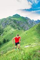 Man climbs steep mountain path with use of sticks photo