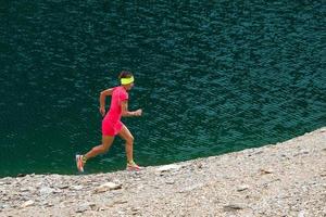 Girl with pink suit runs near a lake photo