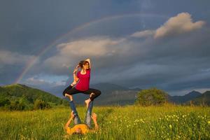 Positions Acroyoga girl of male in nature in the mountains with rainbow in the background. photo