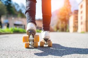 Skater close up in action. Roller skates shoes with sunbeam. photo