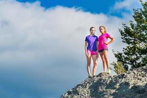 Two young sporty girls standing on top of the mountain - triumph photo