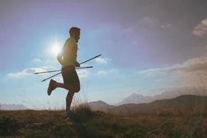 Man runs in the mountains with sticks in his hand photo