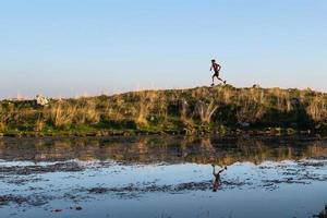 atleta de montaña se refleja en un pequeño lago mientras corre foto