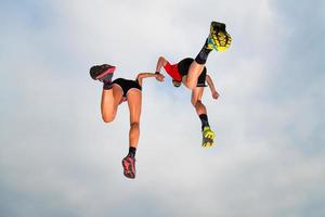 Pair of sportsmen make a jump in the sky hand in hand photo