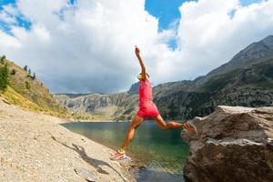 Woman jumps from a rock near a mountain lake photo