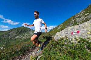 atleta masculino practicando carreras de montaña en un sendero marcado por los alpes oróbicos foto