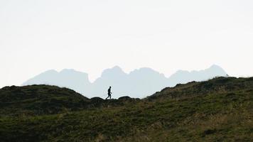 Silhouette of a man who practices Nordic walking in the mountains photo