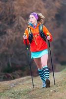 joven rubia práctica activa marcha nórdica en una montaña m foto