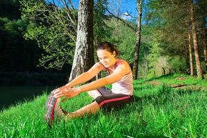 Girl doing training exercise sitting in a green grass. photo