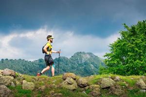 atleta masculino practica la marcha nórdica en el camino de la montaña foto