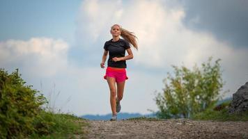 Young girl with lean physique running on hill dirt photo