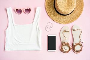 ropa de mujer de verano de moda con accesorios sobre fondo rosa con teléfono inteligente de pantalla vacía, puesta plana, vista superior foto