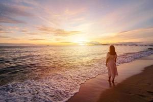 Lonely young woman walking and enjoying beautiful Sunset on the tranquil beach, Travel on summer vacation concept