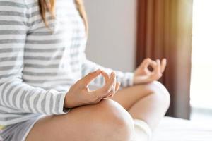 Close up of young woman doing yoga meditating on the bed at home after waking up in the morning, Healthy lifestyle concept photo