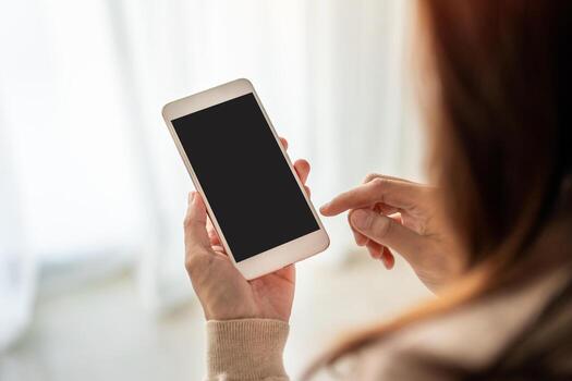 mujer joven sentada en el sofá y usando un teléfono inteligente en casa con espacio para copiar foto