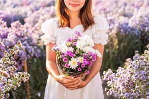 Young woman relaxing and enjoying in blooming flowers field in the morning photo