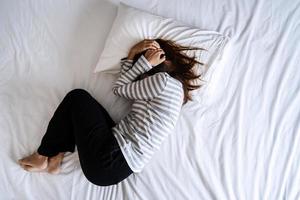 joven solitaria deprimida y estresada en la cama, emoción negativa y concepto de salud mental foto