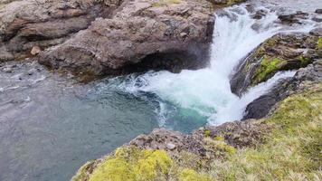 fantastica cascata nel paesaggio dell'Islanda con rocce ed erba. video