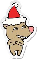 sticker cartoon of a bear showing teeth wearing santa hat vector