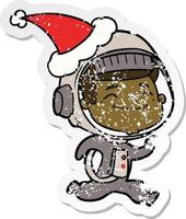 happy distressed sticker cartoon of a astronaut wearing santa hat vector