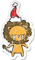 crying distressed sticker cartoon of a lion wearing santa hat vector