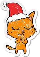 calm distressed sticker cartoon of a cat wearing santa hat vector