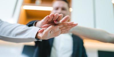 Team of young male and female employees stacking hands on top of each others to depict unity and harmony amongst colleagues for project and positive work environment photo