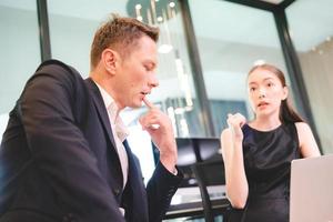 Young female business person in conversation with male manager or colleague or boss while giving presentation on project research work using laptop in conference room in modern office photo